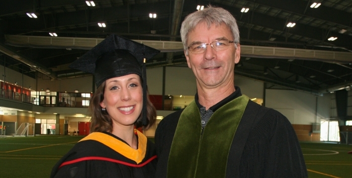 毕业学生Renée Plante戴着帽子，穿着长袍，和Glen Bergeron教授在一起