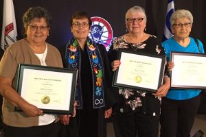 three women posing with President Trimbee holding honorary doctorates